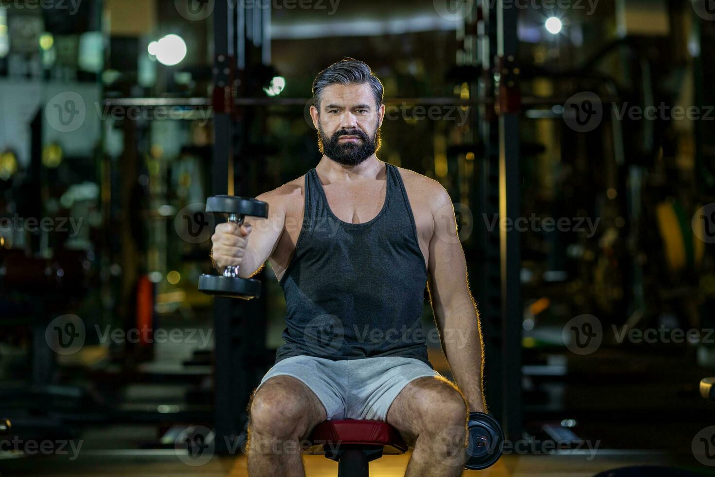 caucasiano barba muscular esporte homem é prática peso Treinamento em haltere para bíceps e tríceps músculo dentro Academia com Sombrio fundo e luz fumaça brilho para exercício e exercite-se foto