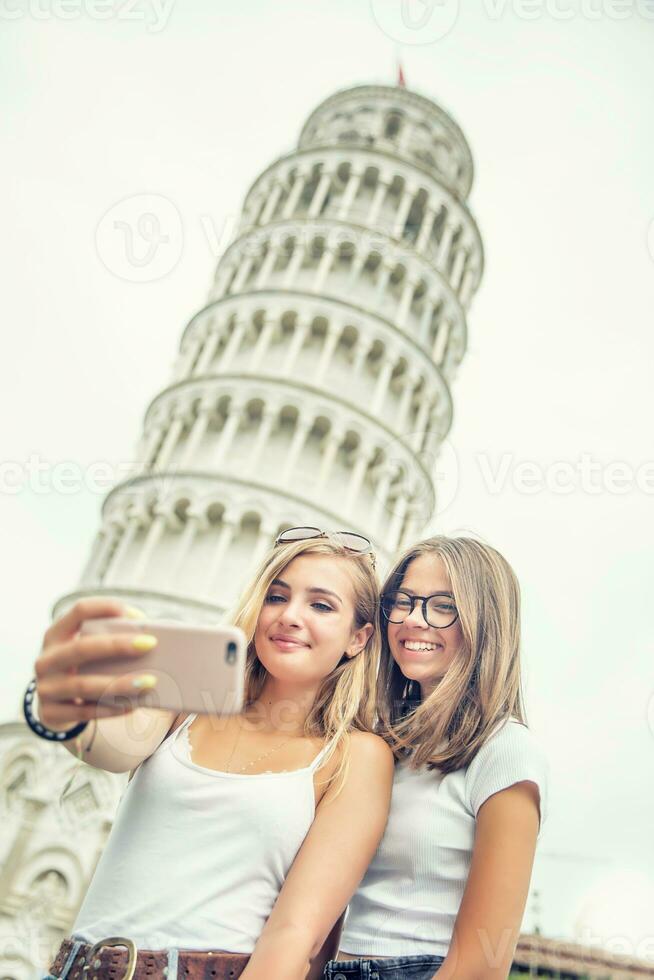 jovem adolescente meninas viajante turista antes pisa torre selfie para Smartphone cenário ou vídeo foto