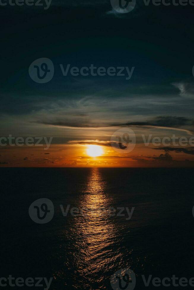 brilhante laranja pôr do sol em a Sombrio indiano oceano em bali ilha. tarde luz solar, fogo céu, surpreendente Visão foto