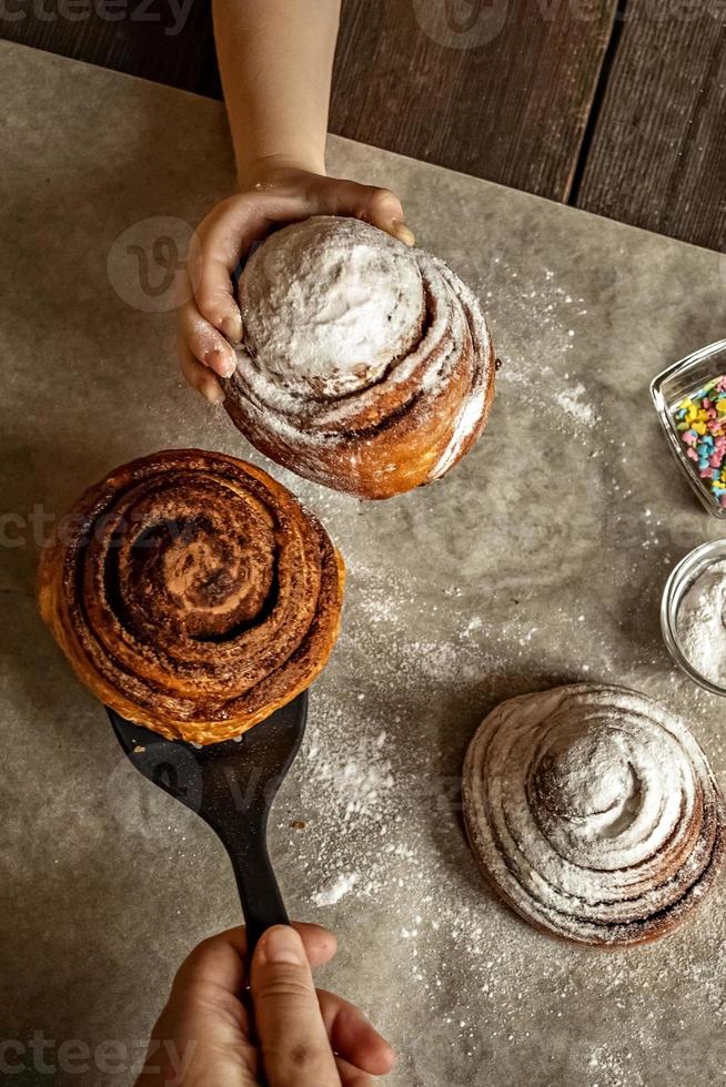 mão de criança pega um pão de canela recém-assado foto