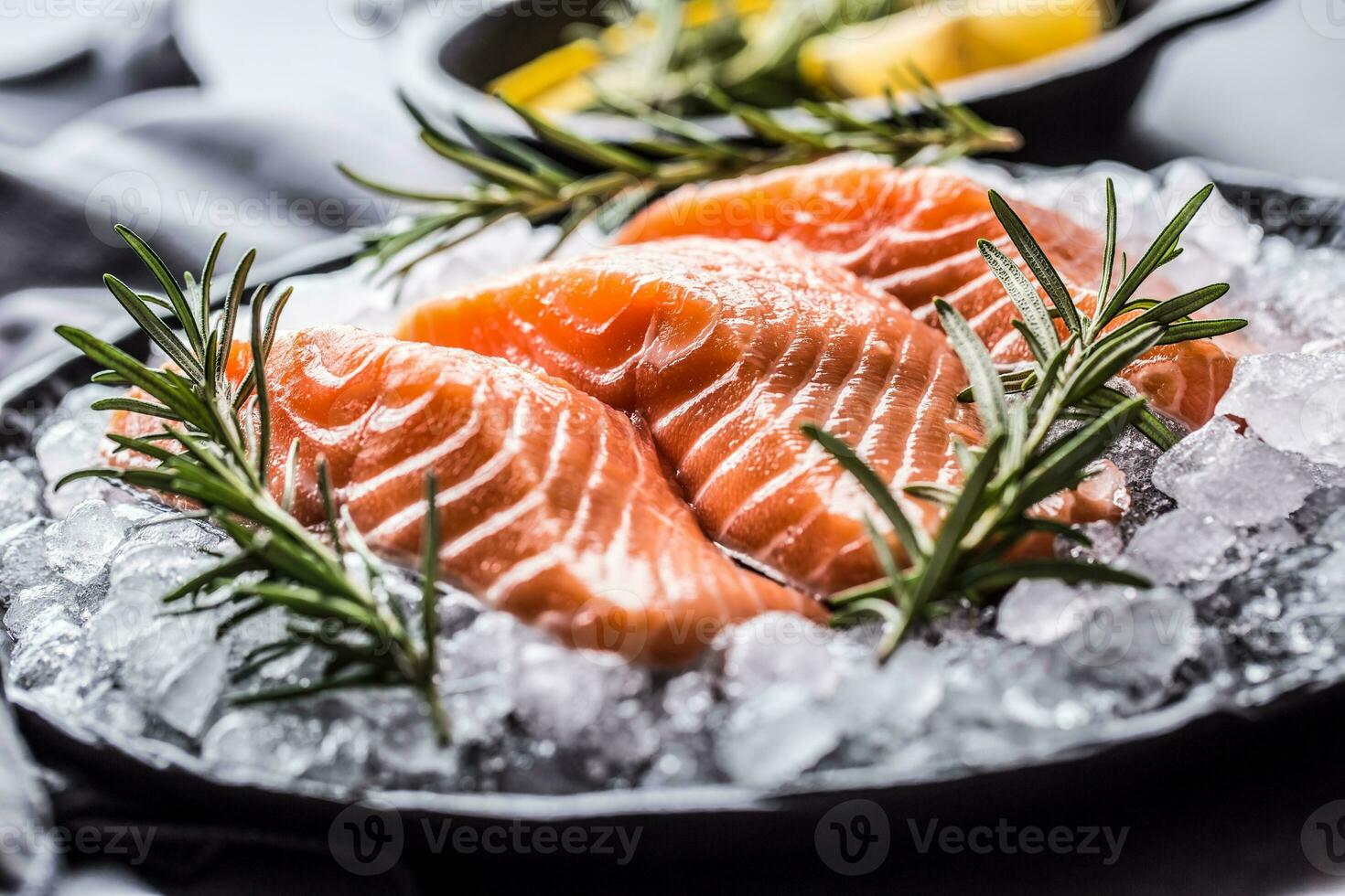 repartido cru salmão filetes dentro gelo em prato com limão e alecrim foto