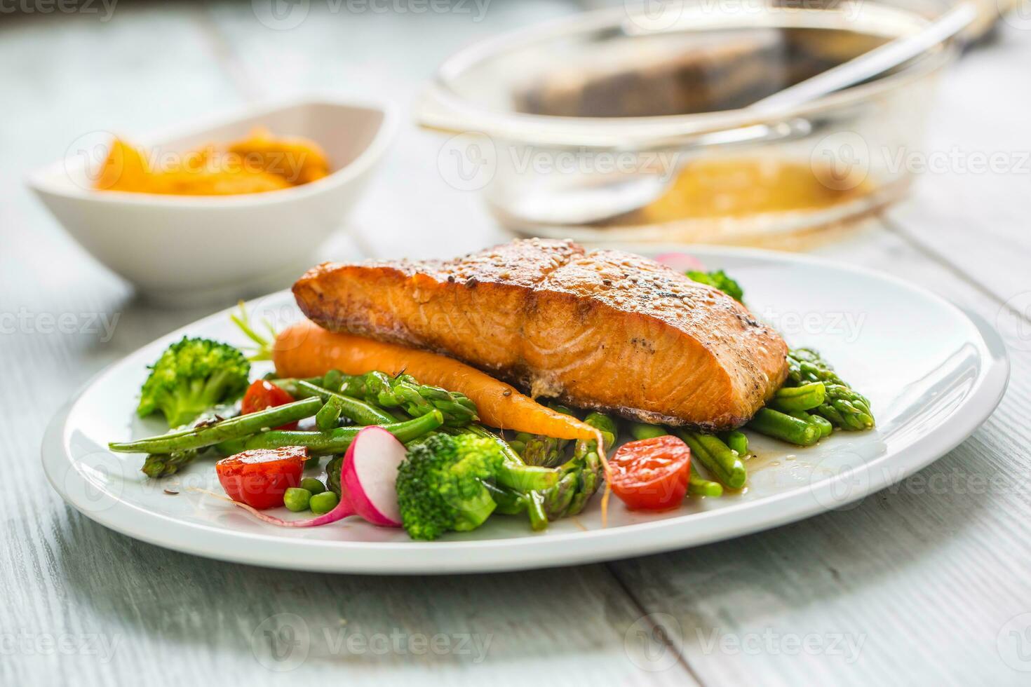 assado salmão bife com espargos brócolis cenoura tomates rabanete verde feijões e ervilhas. peixe refeição com fresco vegetal foto