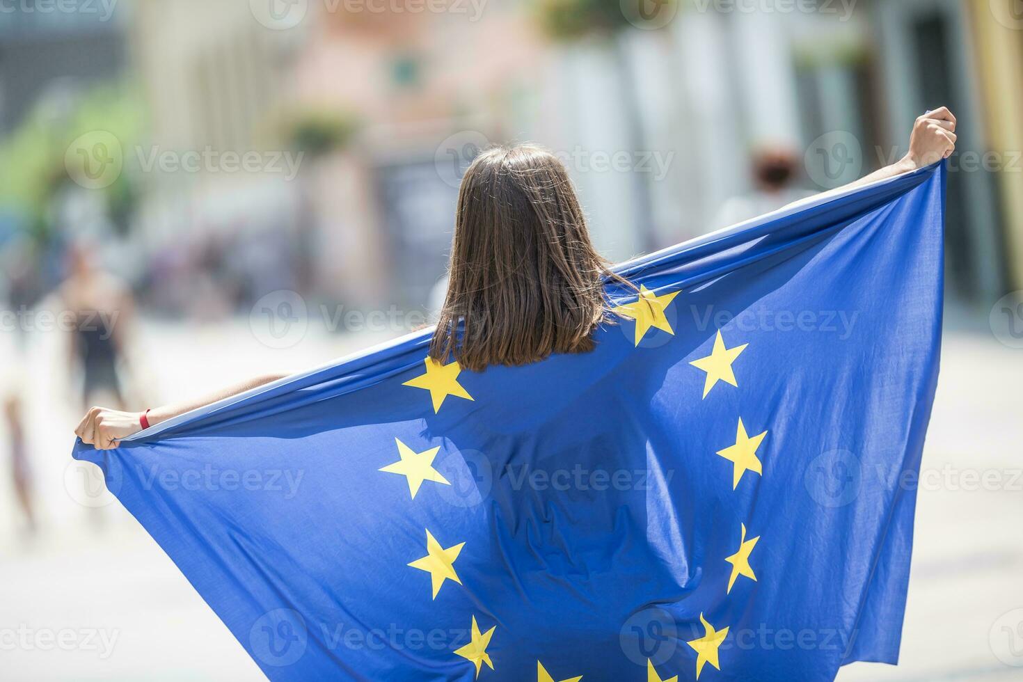 fofa feliz jovem menina com a bandeira do a europeu União dentro a ruas em algum lugar dentro Europa foto