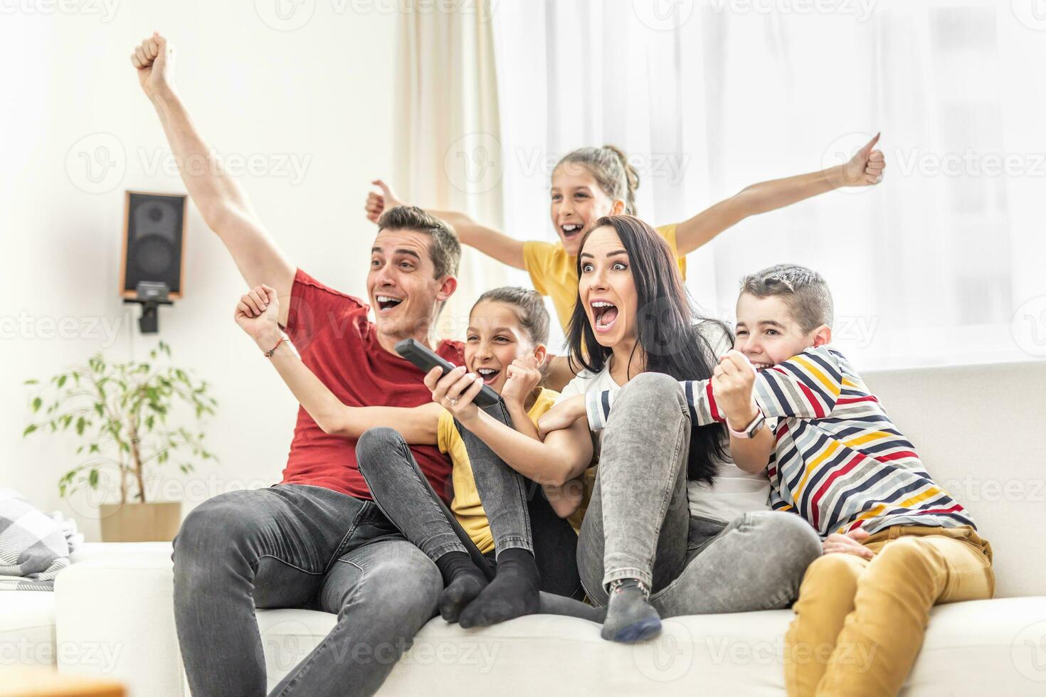 entusiasmado família do cinco Felicidades às casa assistindo Esportes em televisão foto