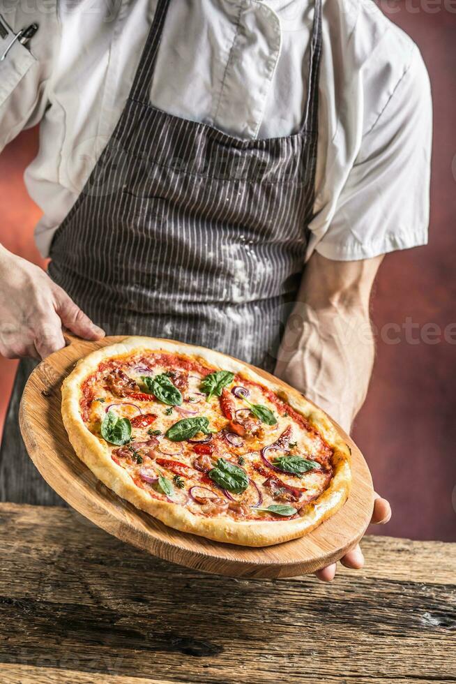 chefe de cozinha e pizza. chefe de cozinha oferta pizza dentro hotel ou restaurante foto