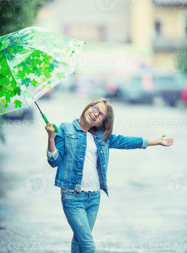 retrato do lindo jovem pré-adolescente menina com guarda-chuva debaixo chuva foto