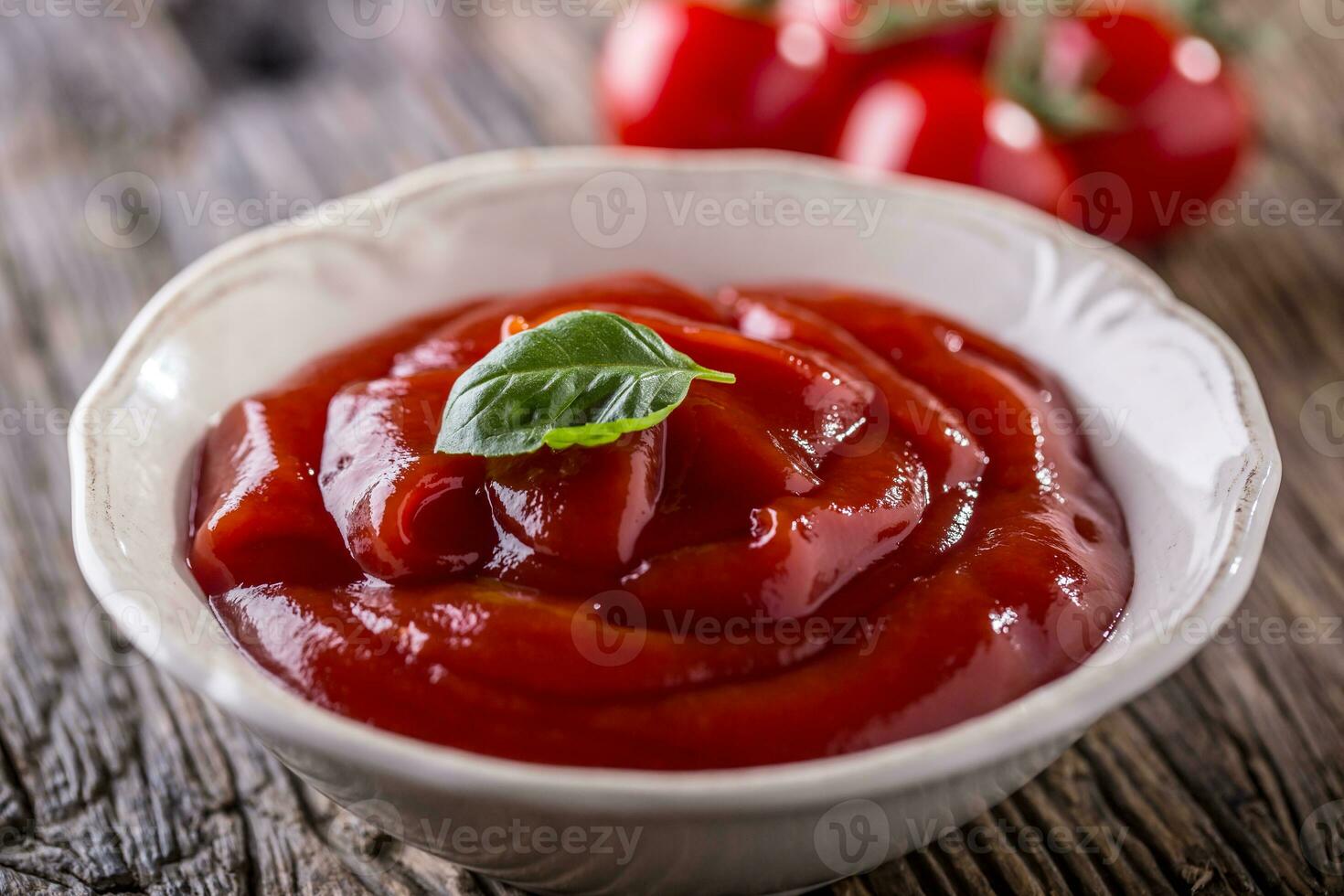 ketchup ou tomate molho dentro branco tigela e cereja tomates em de madeira mesa. foto