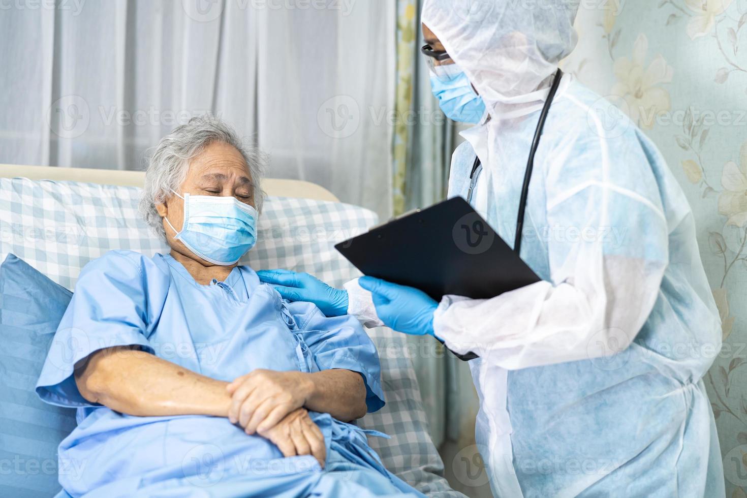 médico asiático usando protetor facial e terno novo normal para verificar o paciente protege a segurança infecção covid-19 surto de coronavírus na enfermaria de quarentena do hospital. foto