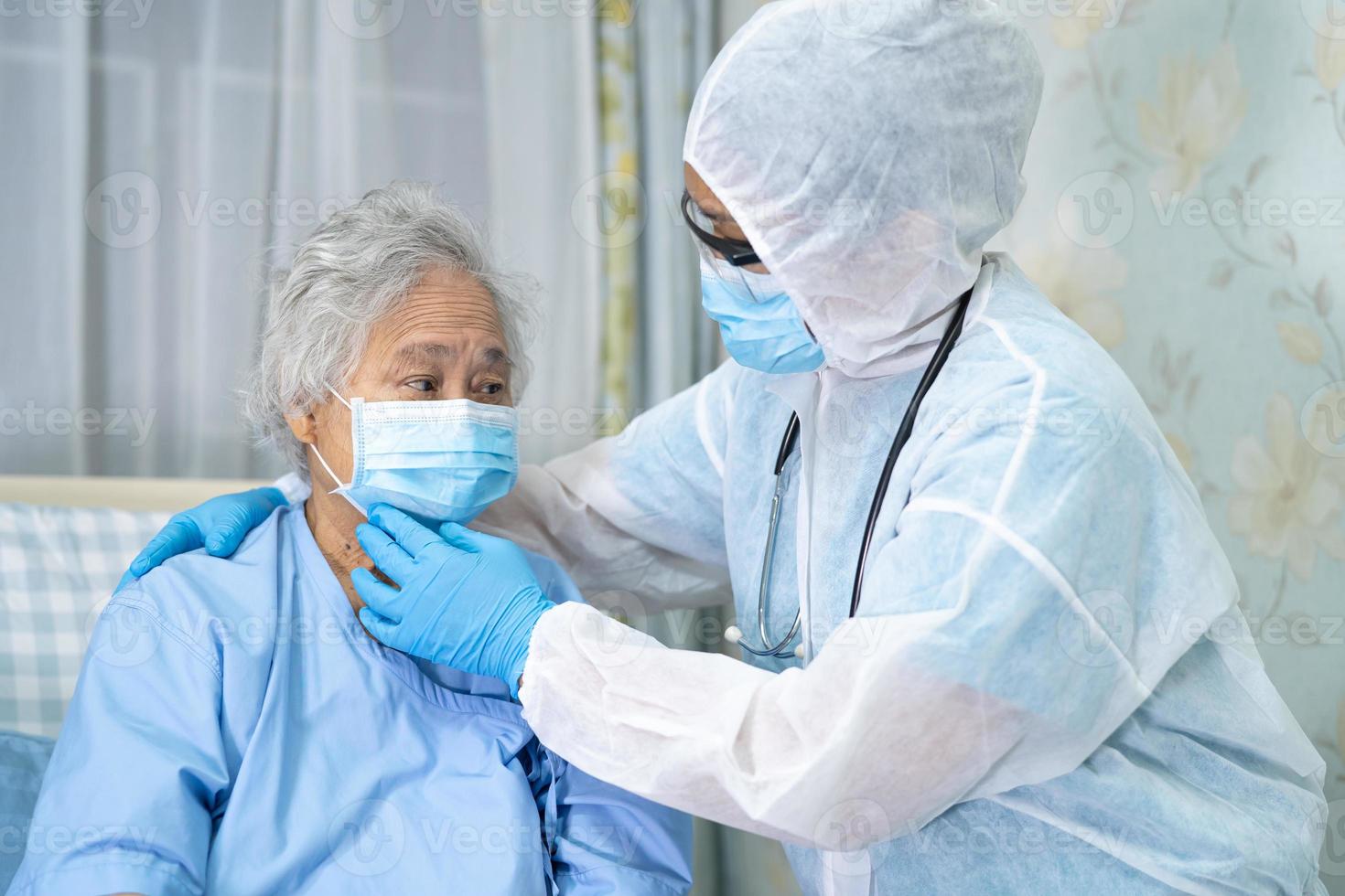 médico asiático usando protetor facial e terno novo normal para verificar o paciente protege a segurança infecção covid-19 surto de coronavírus na enfermaria de quarentena do hospital. foto