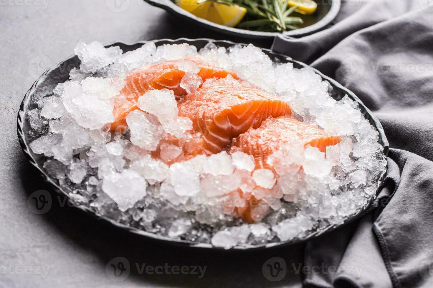 repartido cru salmão filetes dentro gelo em prato com limão e alecrim foto