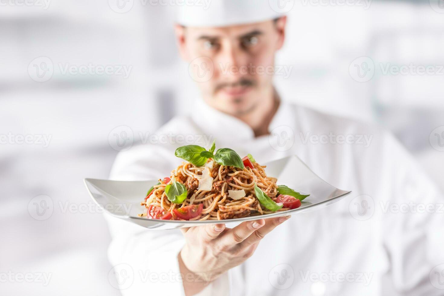 chefe de cozinha dentro restaurante cozinha segurando prato com italiano refeição espaguete bolonhesa foto
