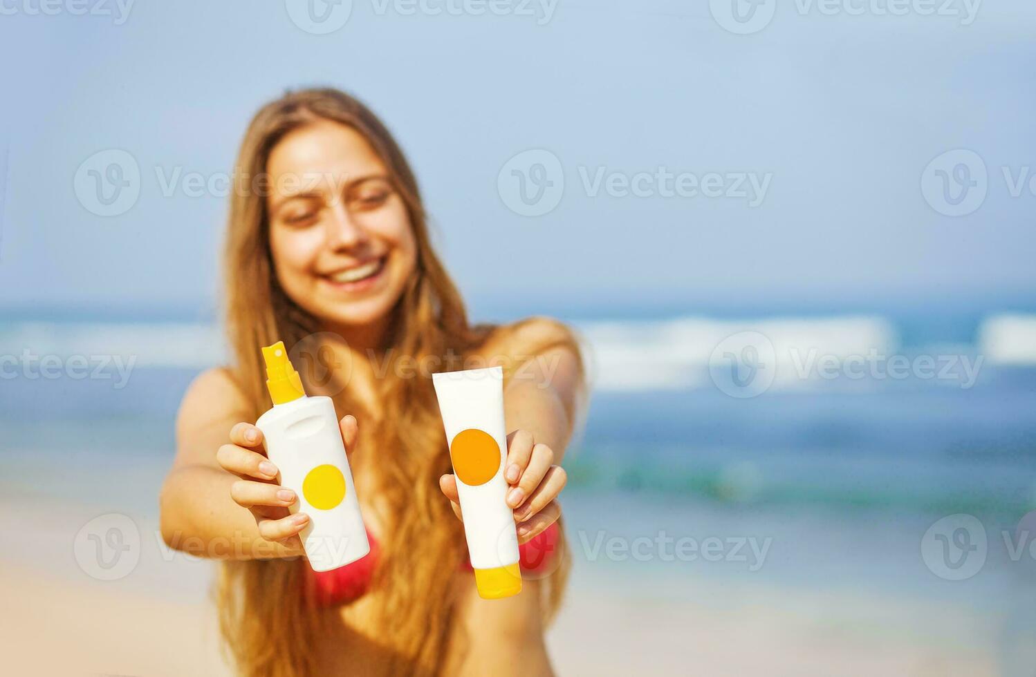 uma mulher dentro uma bikini segurando dois tubos do protetor solar foto