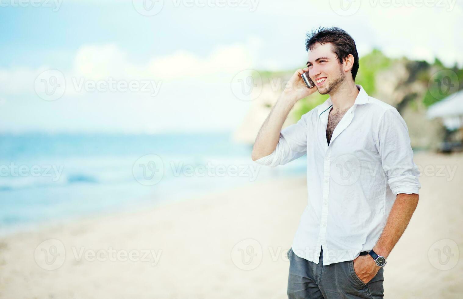 uma homem em a de praia falando em uma célula telefone foto