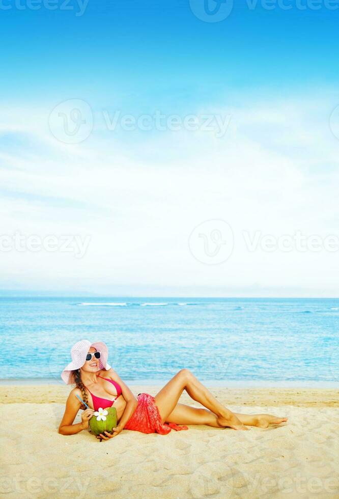 uma mulher dentro uma Rosa vestir deitado em a de praia foto