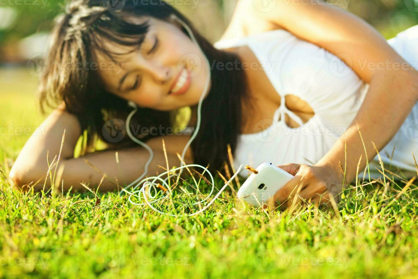 uma mulher deitado em a Relva com fones de ouvido foto