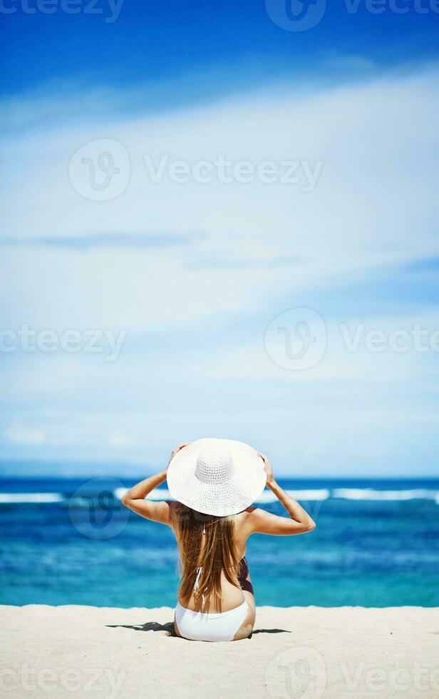 uma mulher dentro uma branco chapéu sentado em a de praia foto