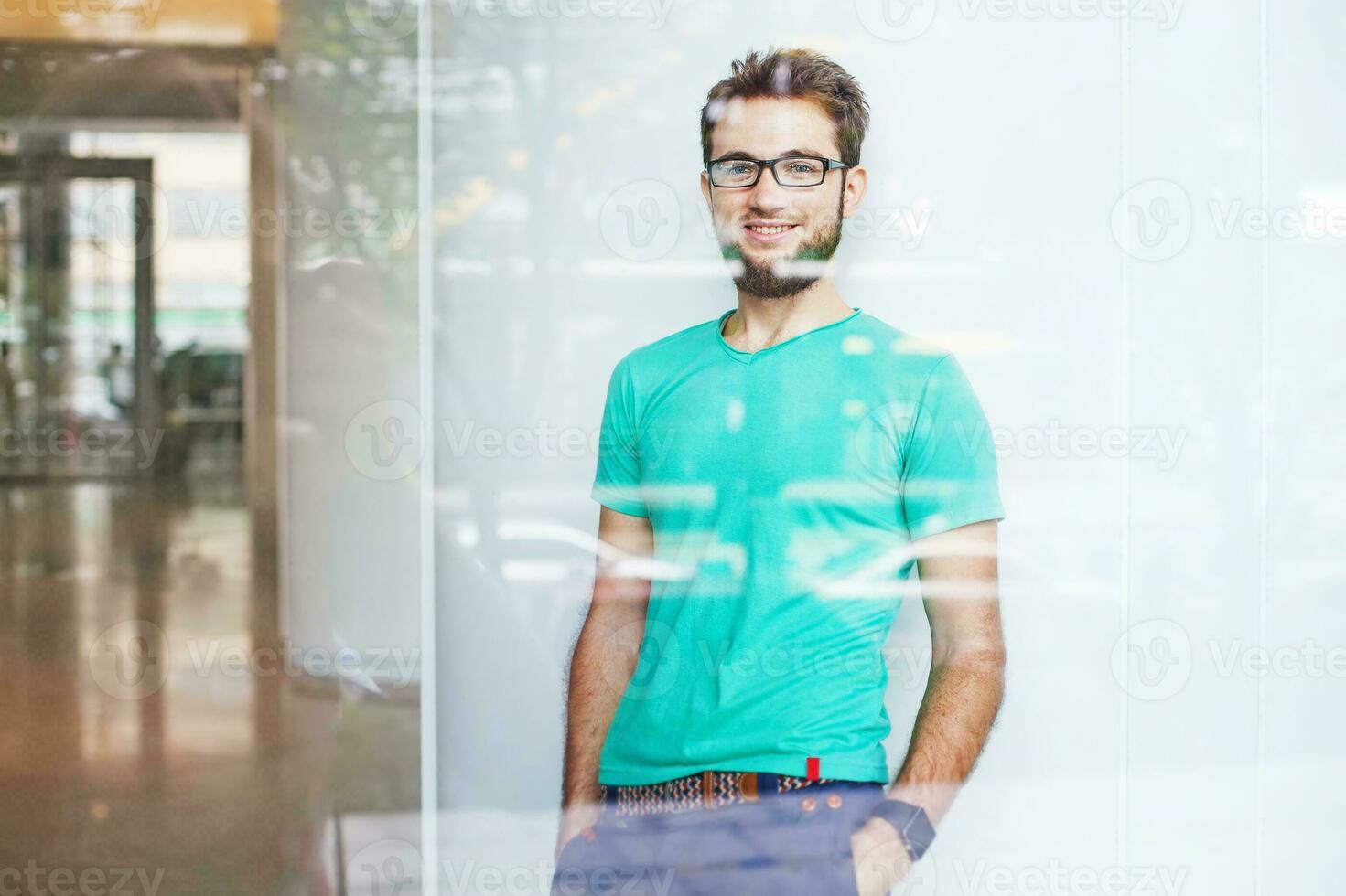 uma homem com óculos e uma barba em pé dentro frente do uma construção foto