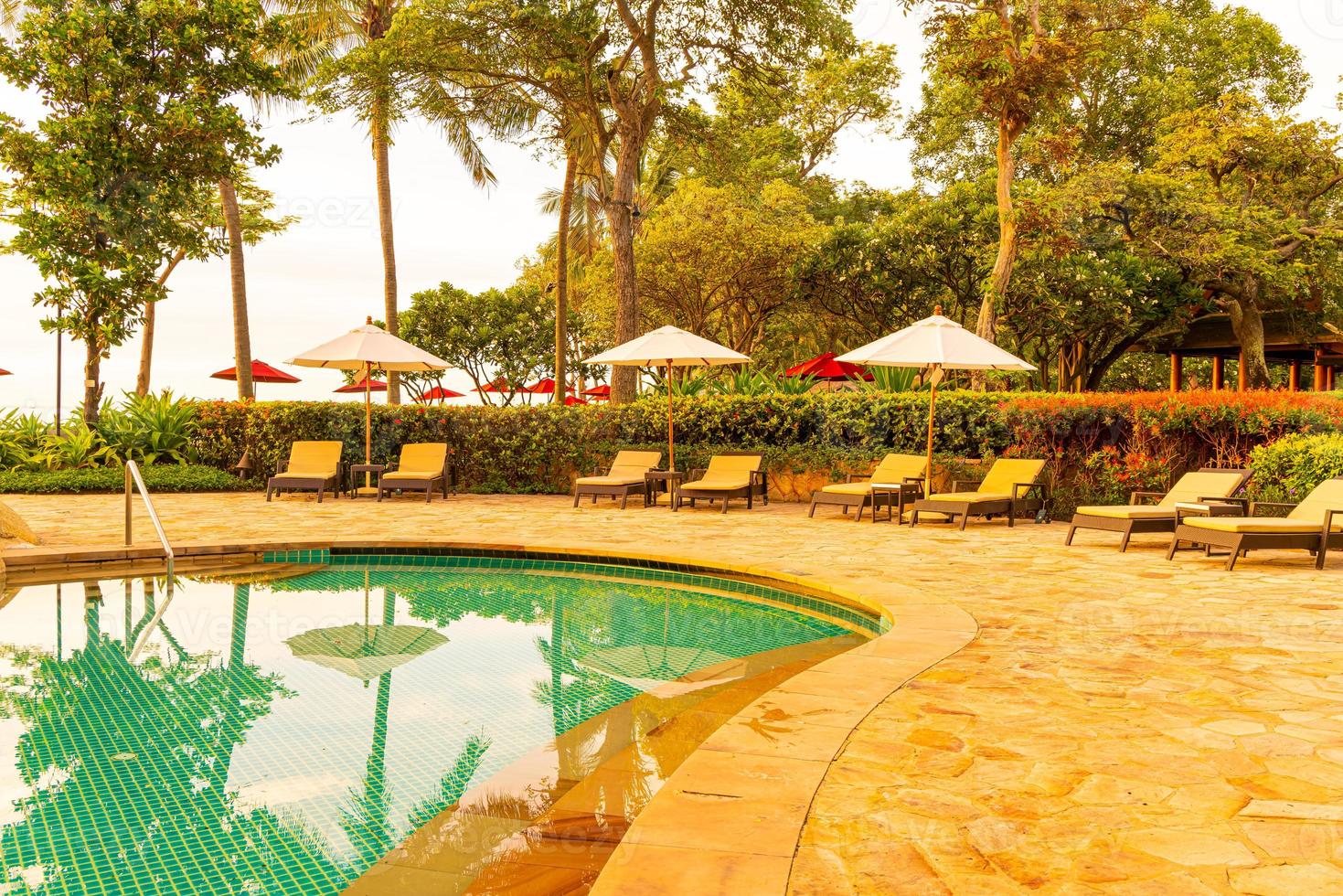 guarda-sol e cadeira ao redor da piscina em hotel resort para viagens de lazer e férias perto da praia do mar foto