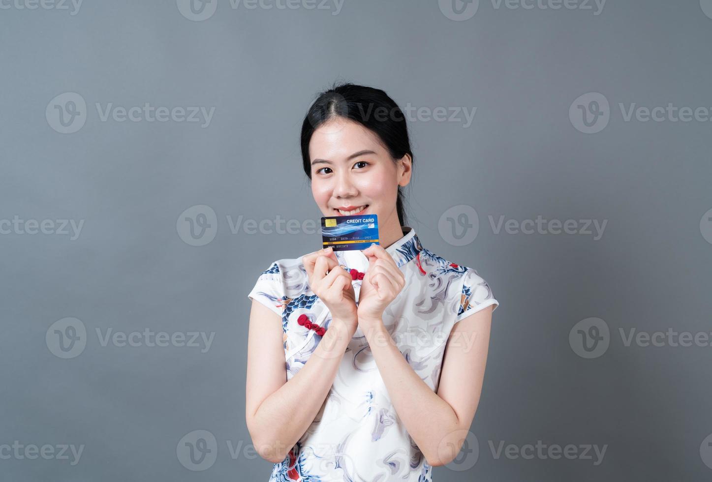 Mulher asiática usando vestido tradicional chinês com a mão segurando um cartão de crédito foto