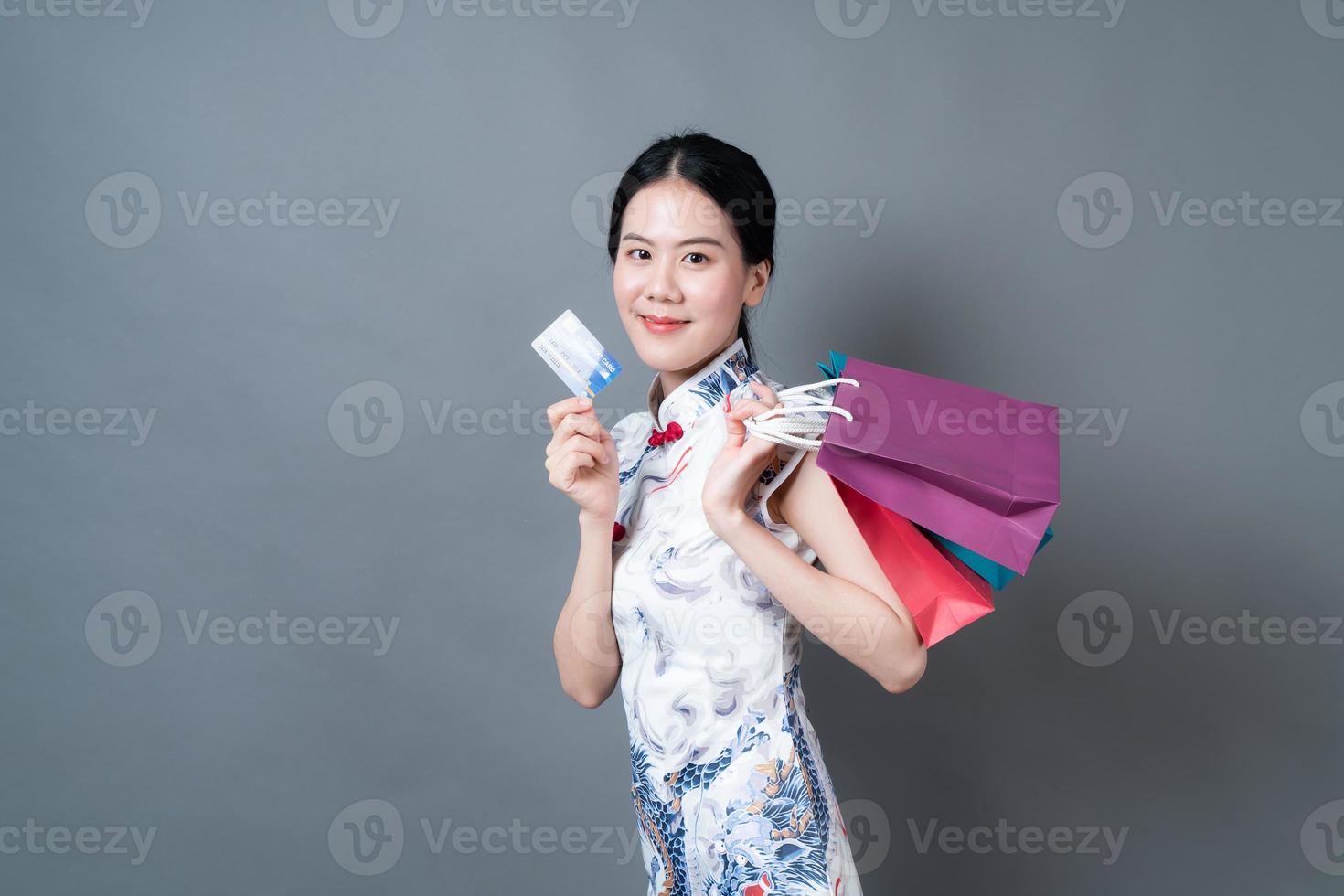 Mulher asiática usa vestido tradicional chinês com sacola de compras e cartão de crédito foto