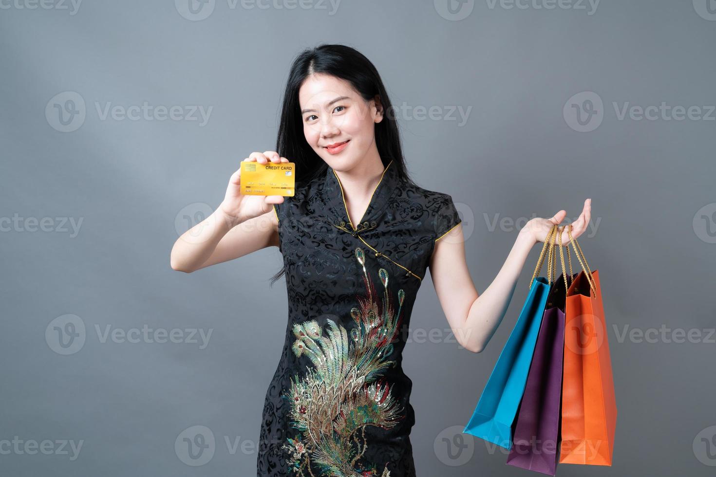 Mulher asiática usa vestido tradicional chinês com sacola de compras e cartão de crédito foto