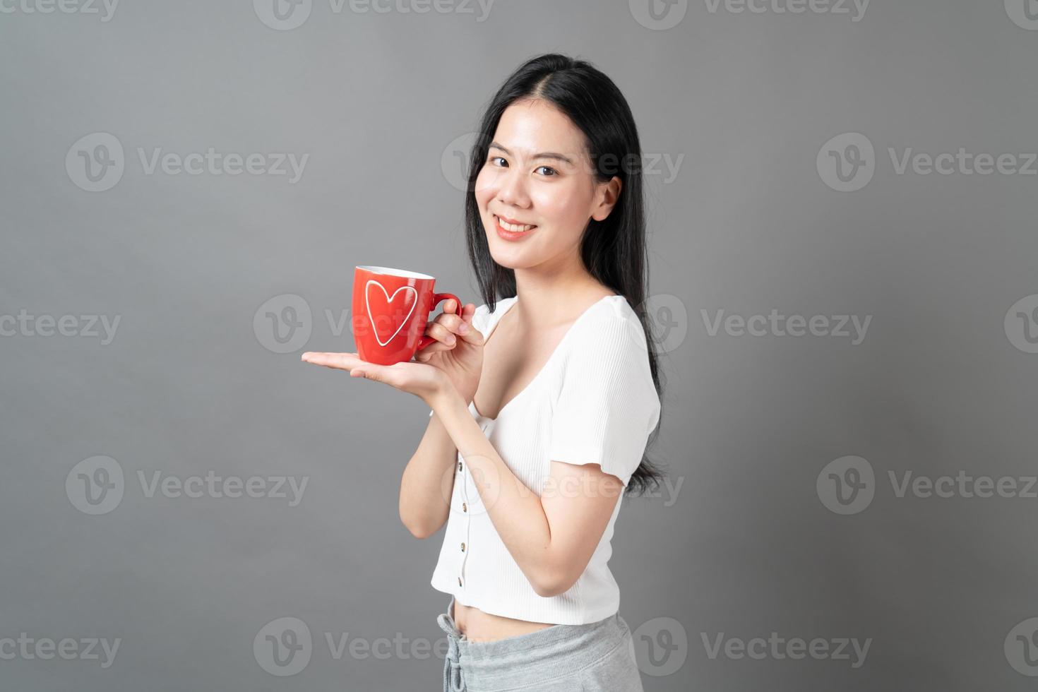 jovem mulher asiática com um rosto feliz e uma mão segurando uma xícara de café foto