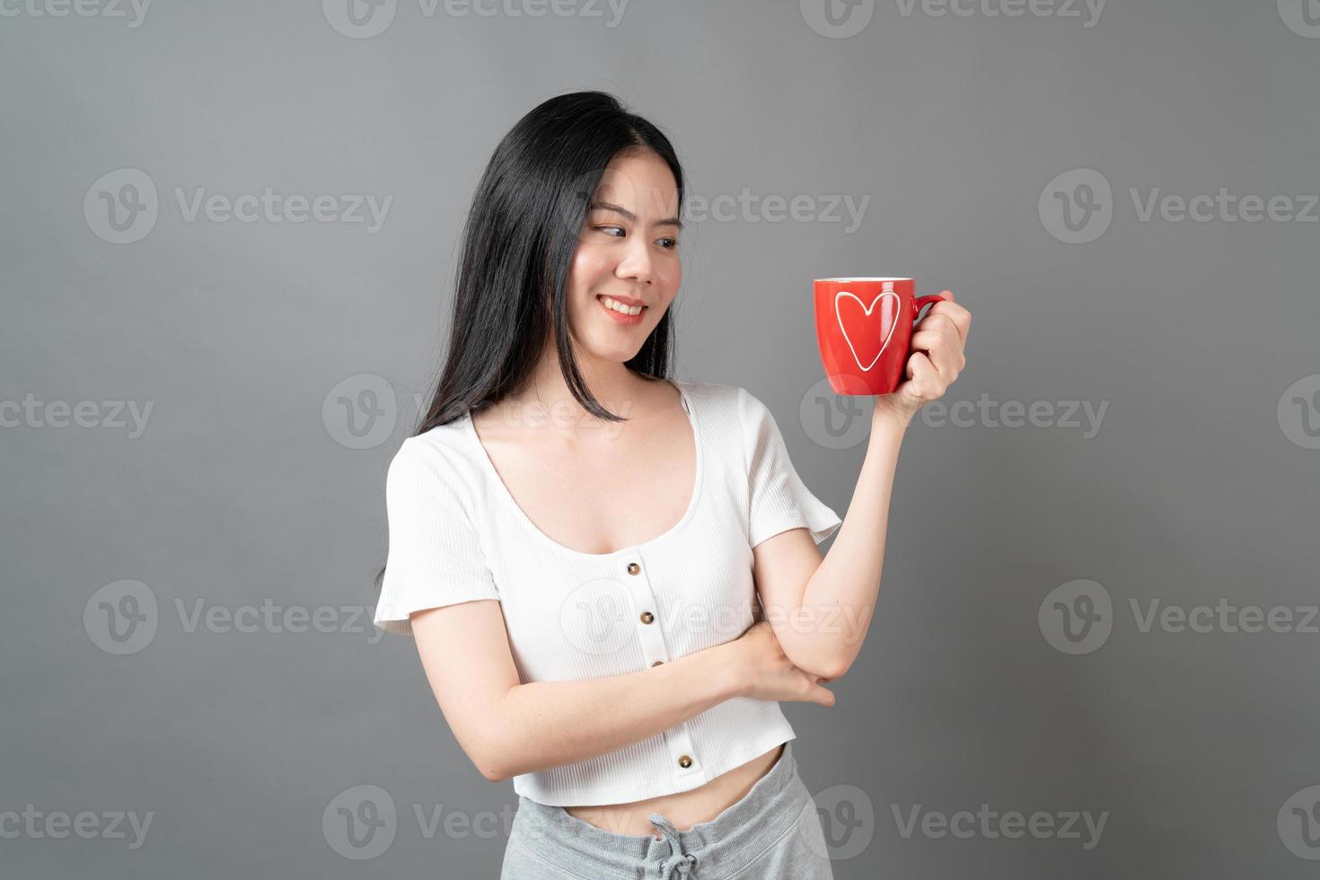 jovem mulher asiática com um rosto feliz e uma mão segurando uma xícara de café foto