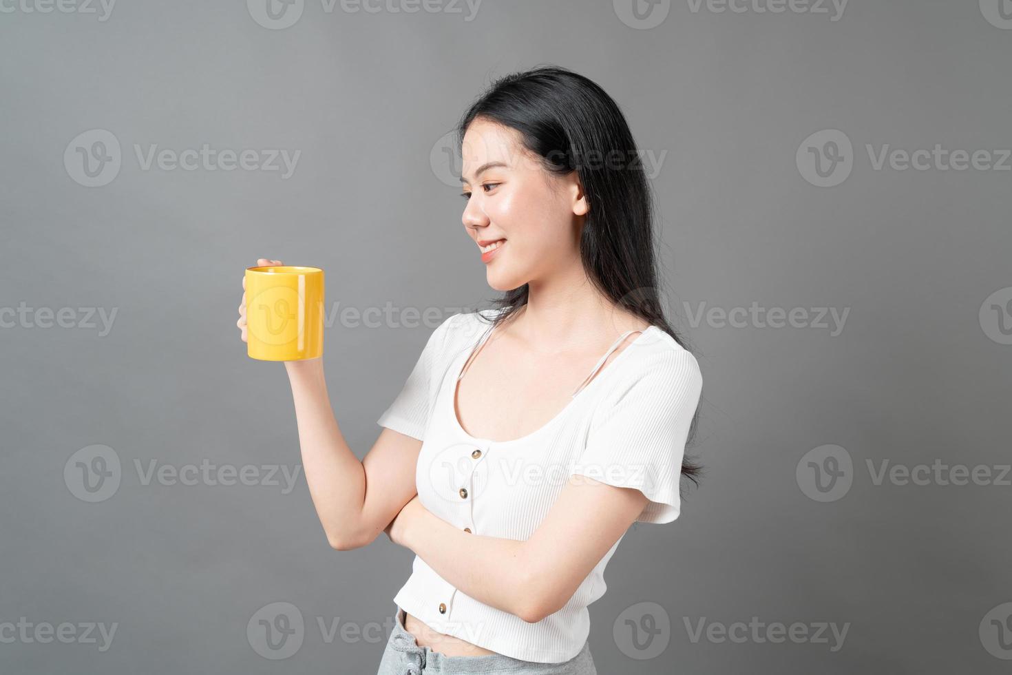 jovem mulher asiática com um rosto feliz e uma mão segurando uma xícara de café foto