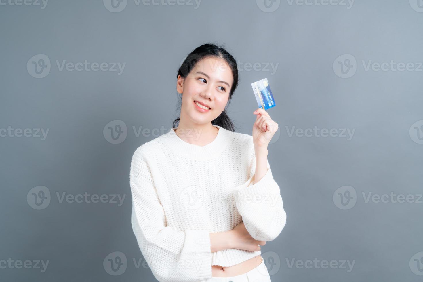 retrato de uma linda jovem asiática de suéter mostrando um cartão de crédito com espaço de cópia foto