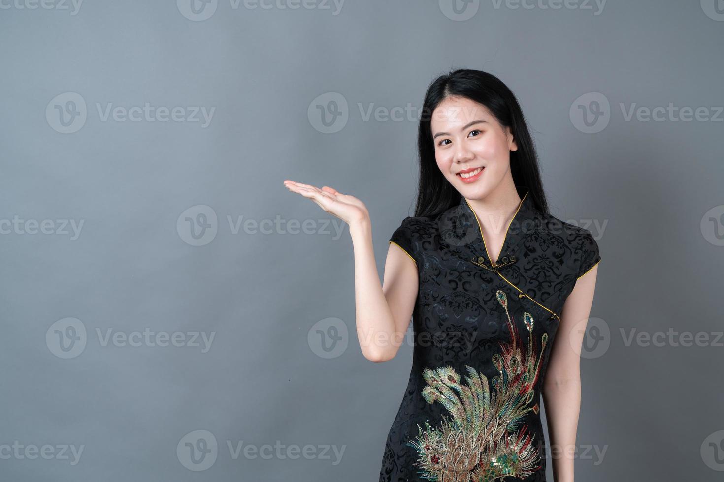 bela jovem asiática usa um vestido tradicional chinês com a mão se apresentando na lateral foto