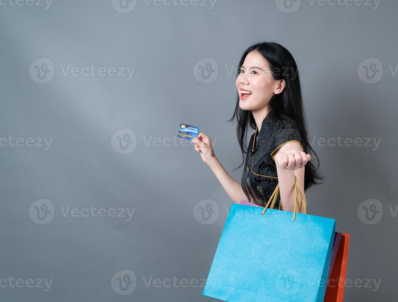 Mulher asiática usa vestido tradicional chinês com sacola de compras e cartão de crédito foto