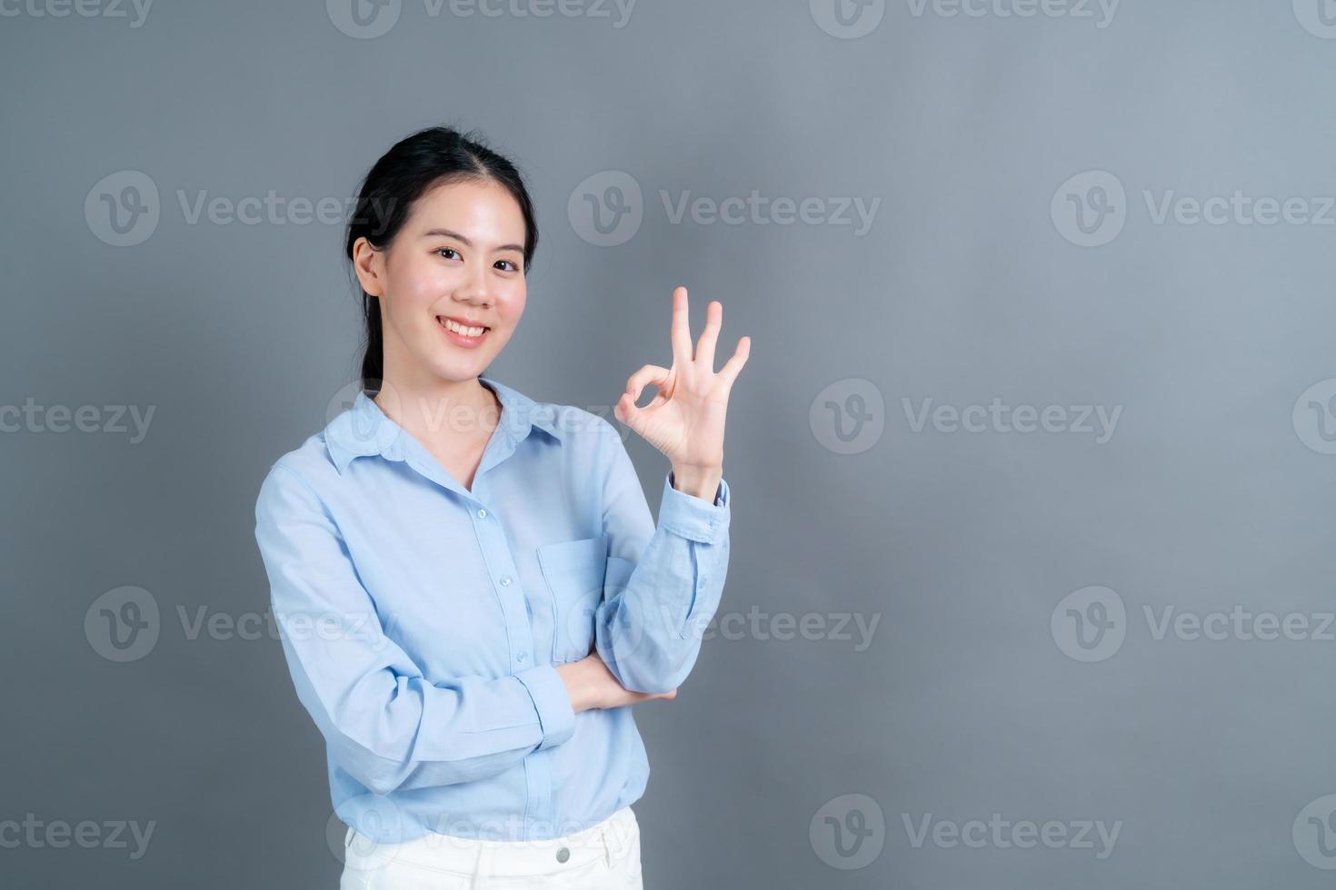 jovem mulher asiática sorrindo e mostrando sinal de ok foto