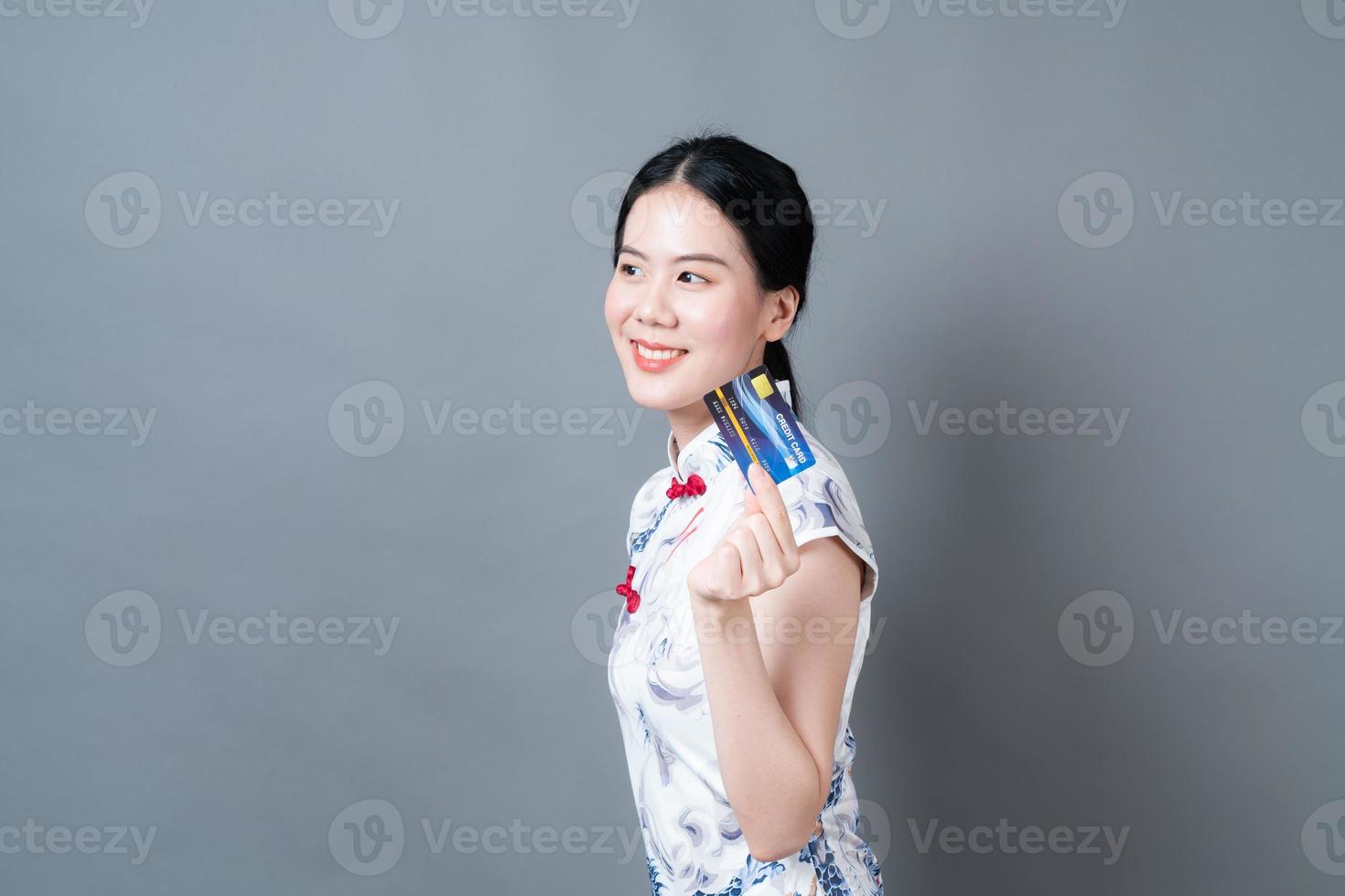 Mulher asiática usando vestido tradicional chinês com a mão segurando um cartão de crédito foto