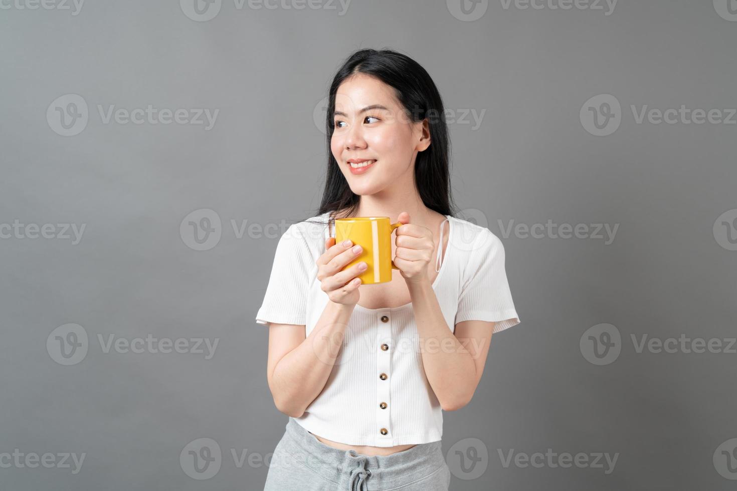 jovem mulher asiática com um rosto feliz e uma mão segurando uma xícara de café foto