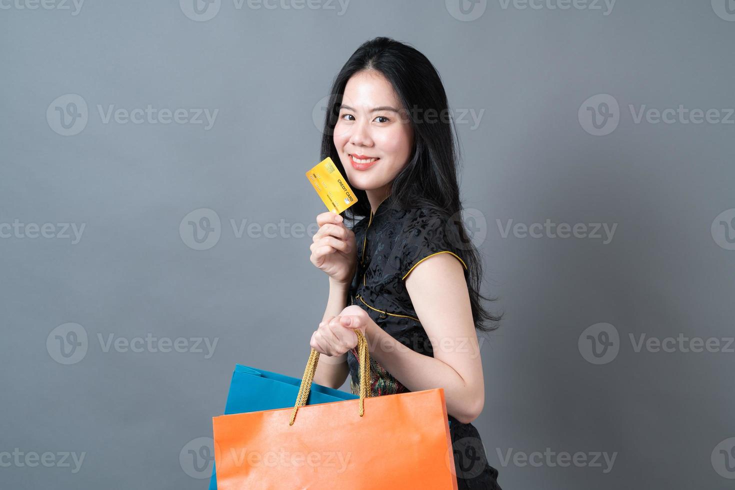 Mulher asiática usa vestido tradicional chinês com sacola de compras e cartão de crédito foto