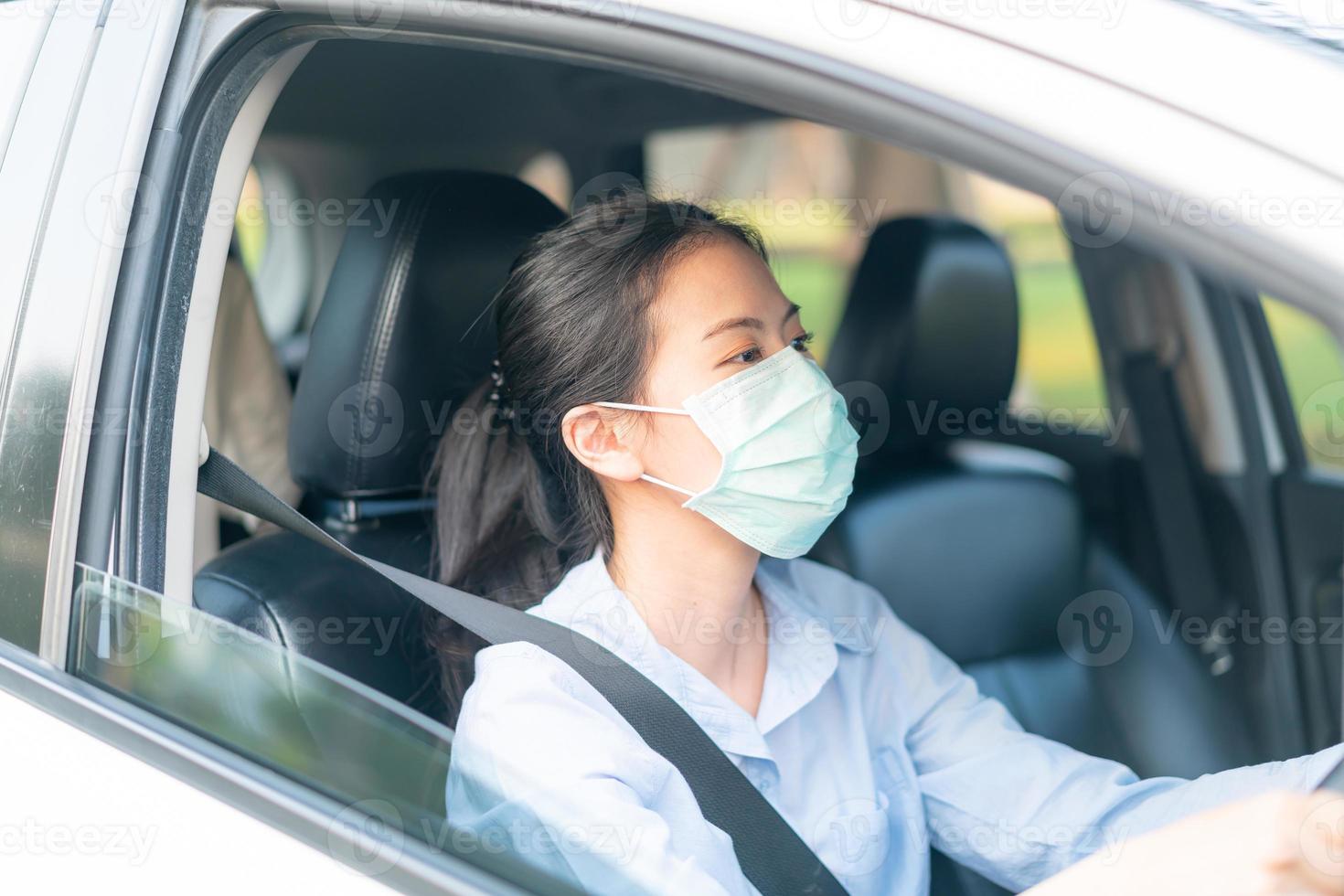 Linda mulher asiática dirigindo um carro usando máscara, indo para fora, mantenha-se saudável, protegendo contra o vírus covid-19 do coronavírus foto