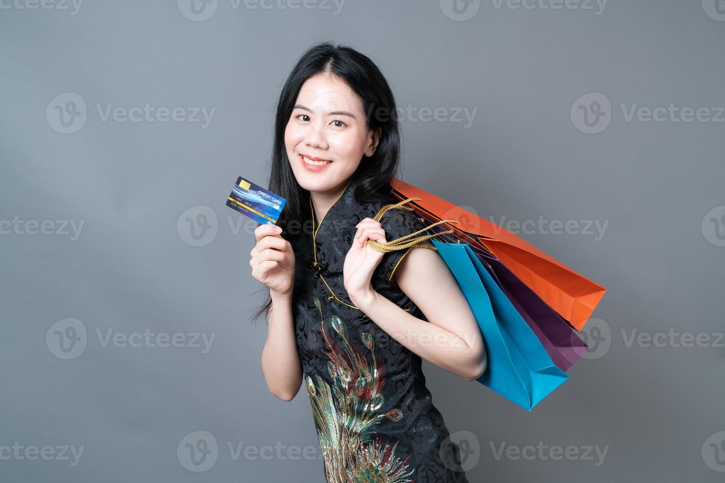 Mulher asiática usa vestido tradicional chinês com sacola de compras e cartão de crédito foto