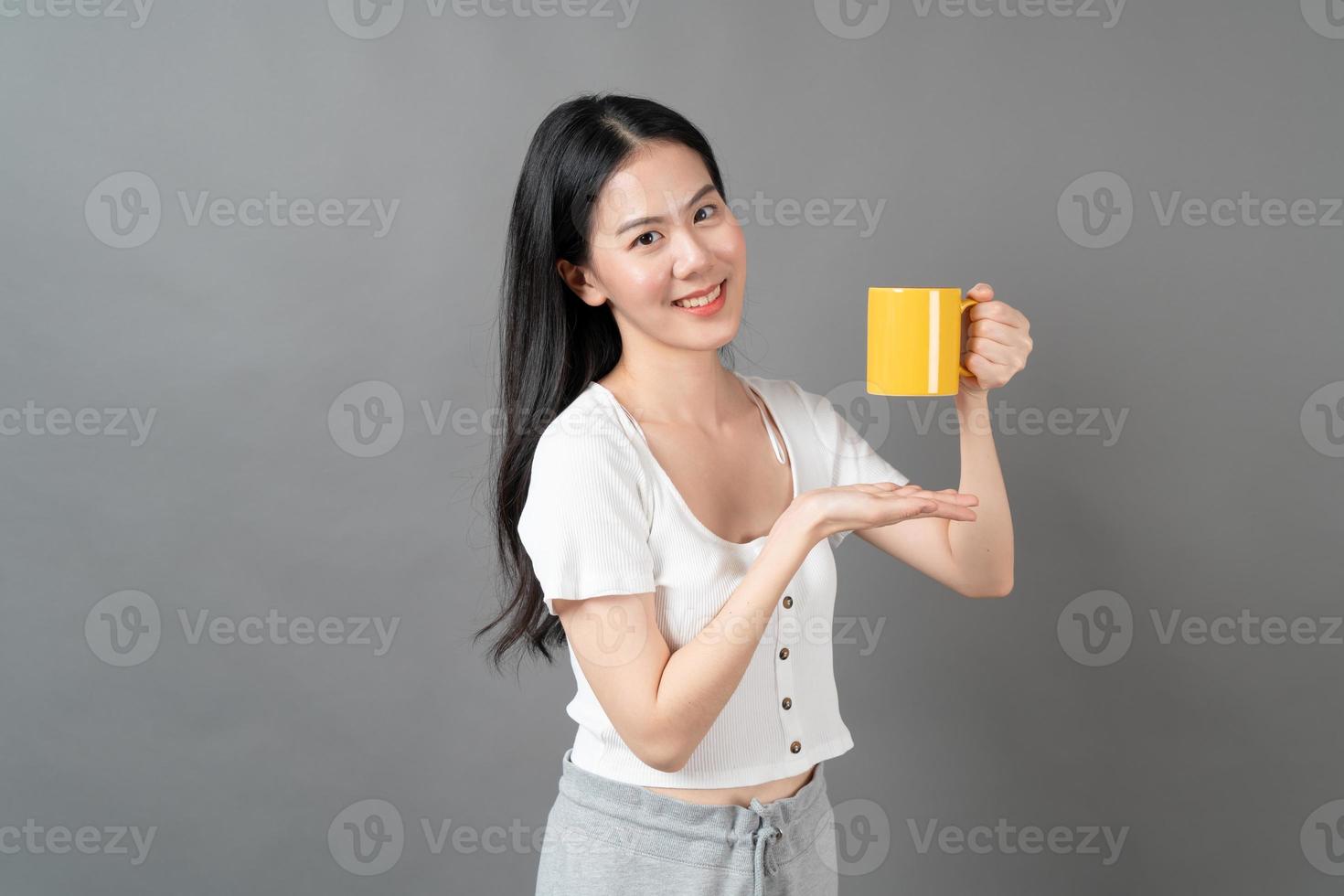 jovem mulher asiática com um rosto feliz e uma mão segurando uma xícara de café foto