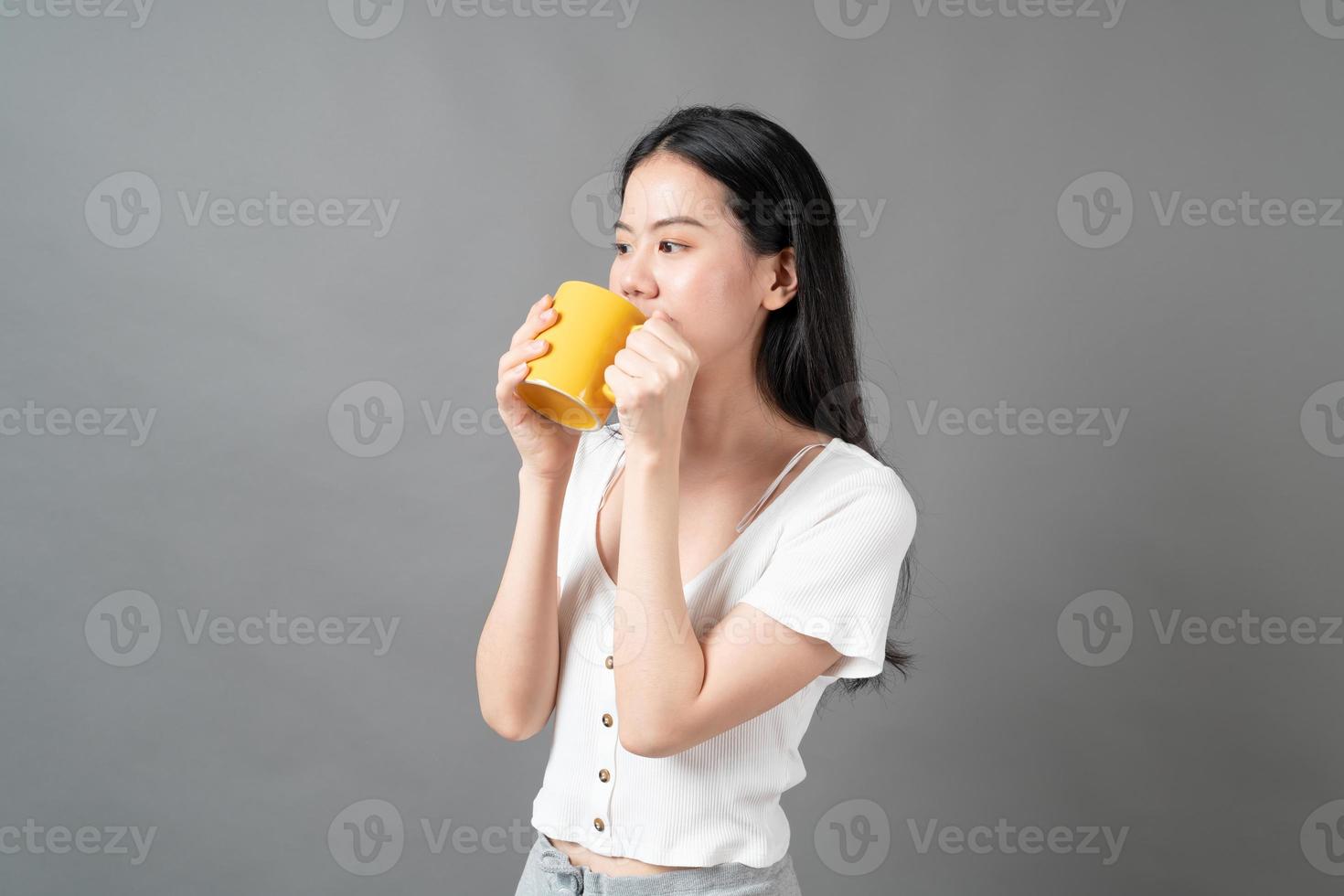 jovem mulher asiática com um rosto feliz e uma mão segurando uma xícara de café foto