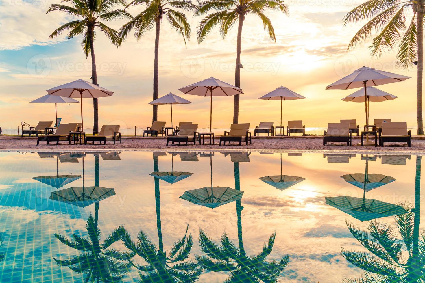 guarda-sol e cadeira ao redor da piscina em hotel resort para viagens de lazer e férias perto da praia do mar foto