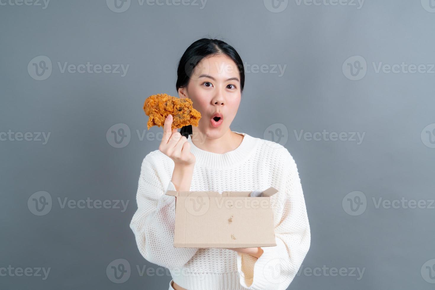 jovem mulher asiática com cara feliz e gosta de comer frango frito foto