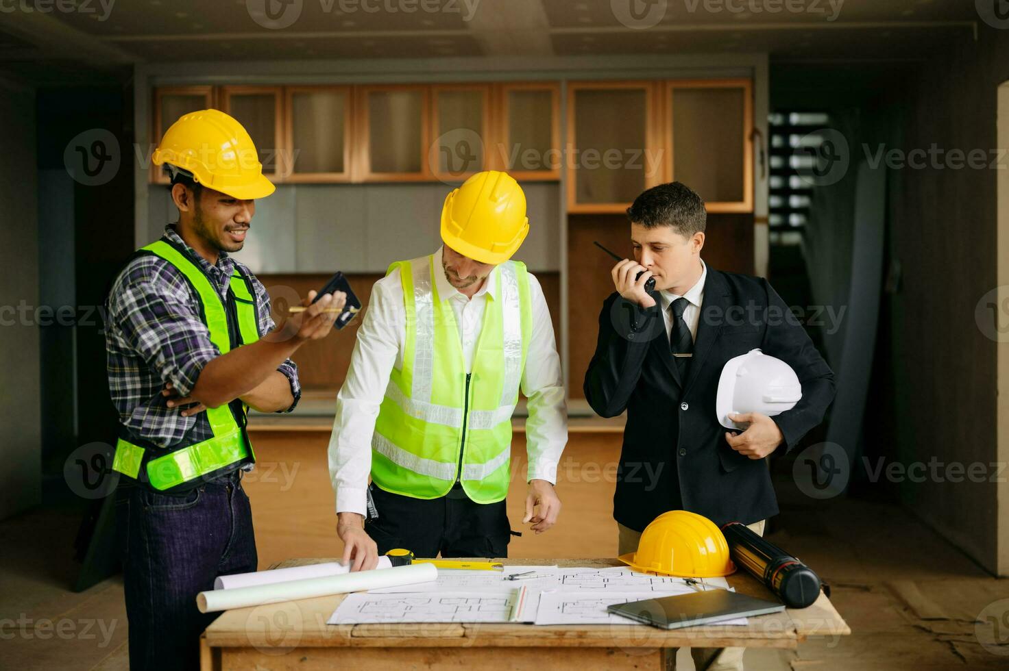 contratante e arquiteto olhando às plano, tábua, computador portátil e falando sobre trabalhando em grande projeto. construção dentro construção processo foto