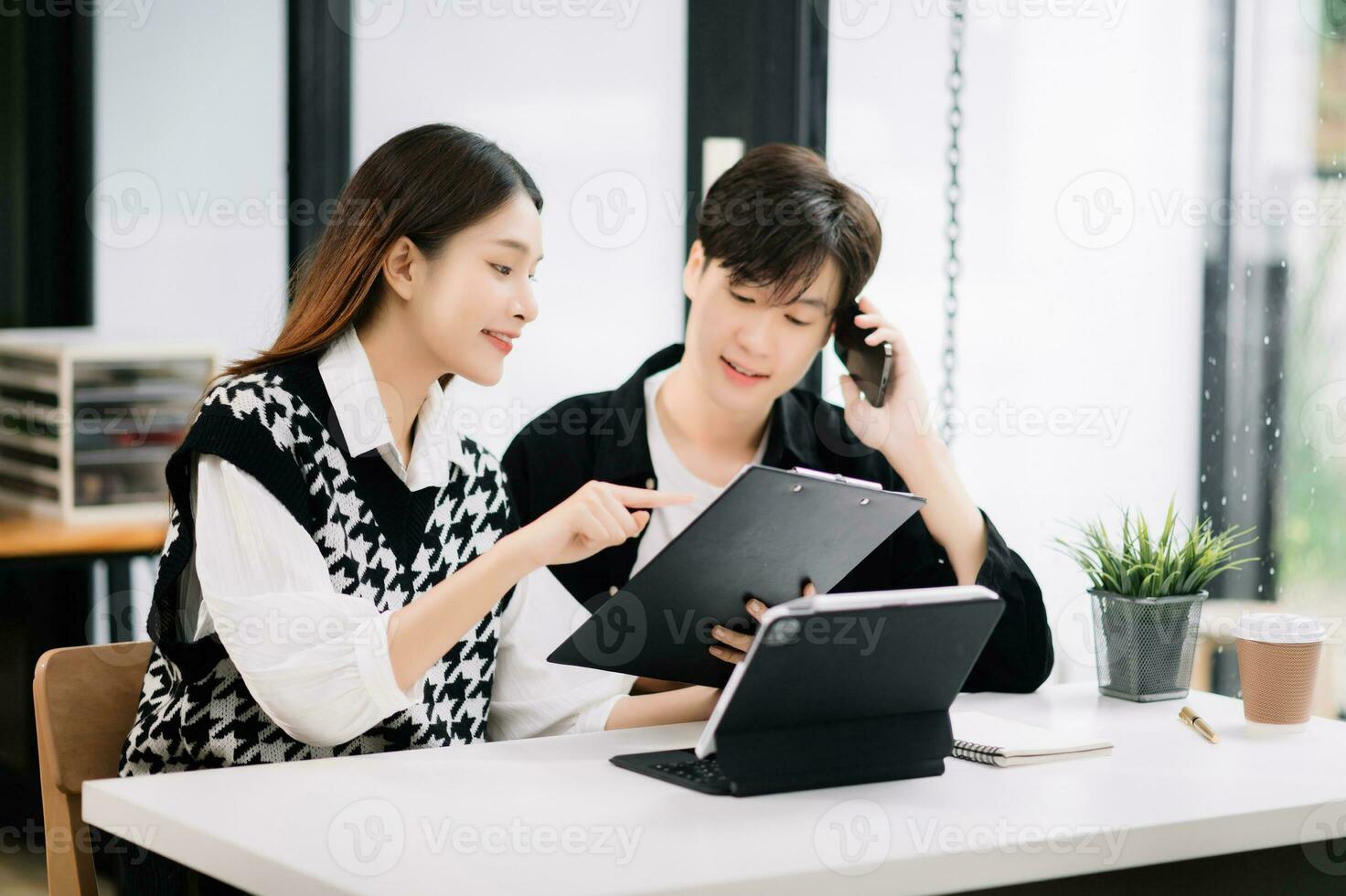 dois ásia o negócio trabalhadores falando em a Smartphone e usando computador portátil às a moderno escritório. foto