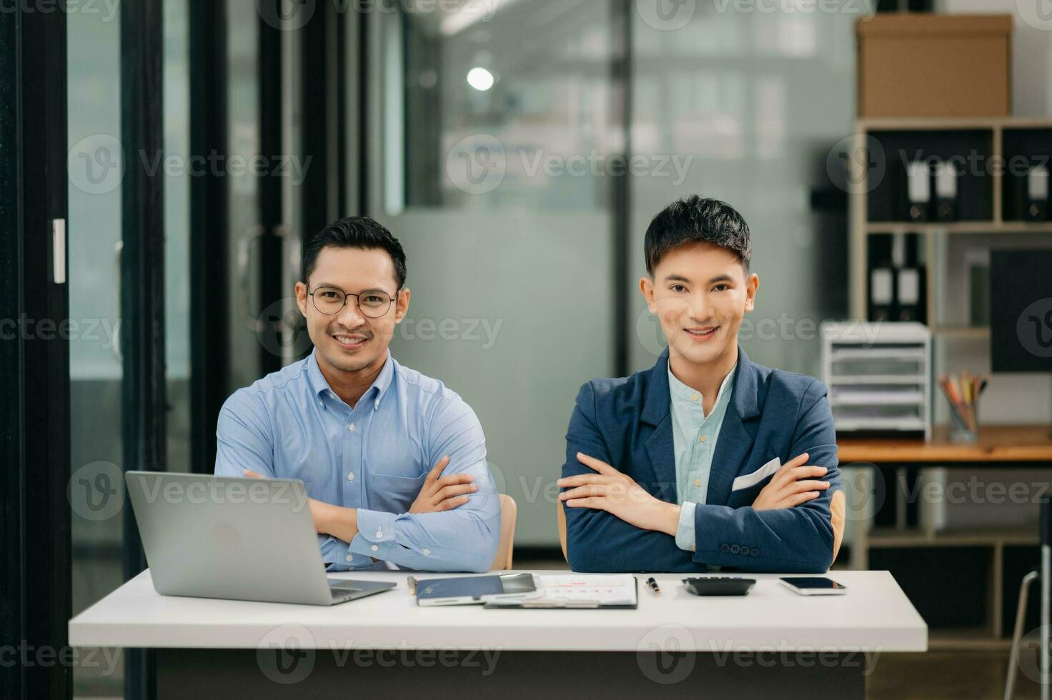 dois ásia o negócio trabalhadores falando em a Smartphone, tábua e usando computador portátil às a escritório. foto