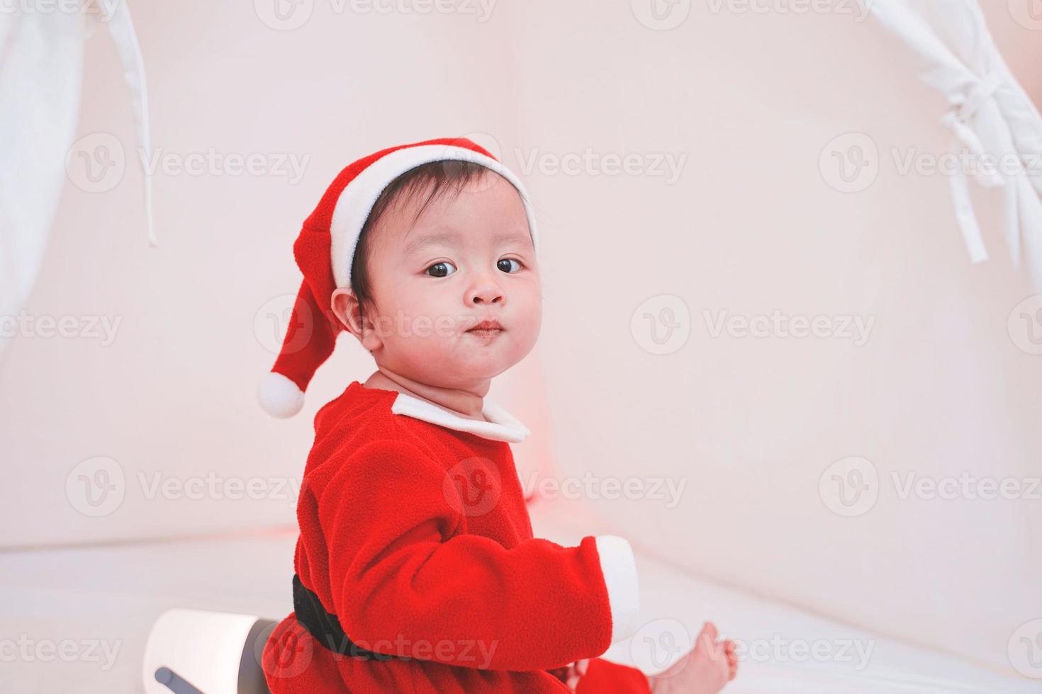 menina asiática em uma fantasia de Papai Noel. lindo bebezinho celebra o Natal. bebê de natal. foto