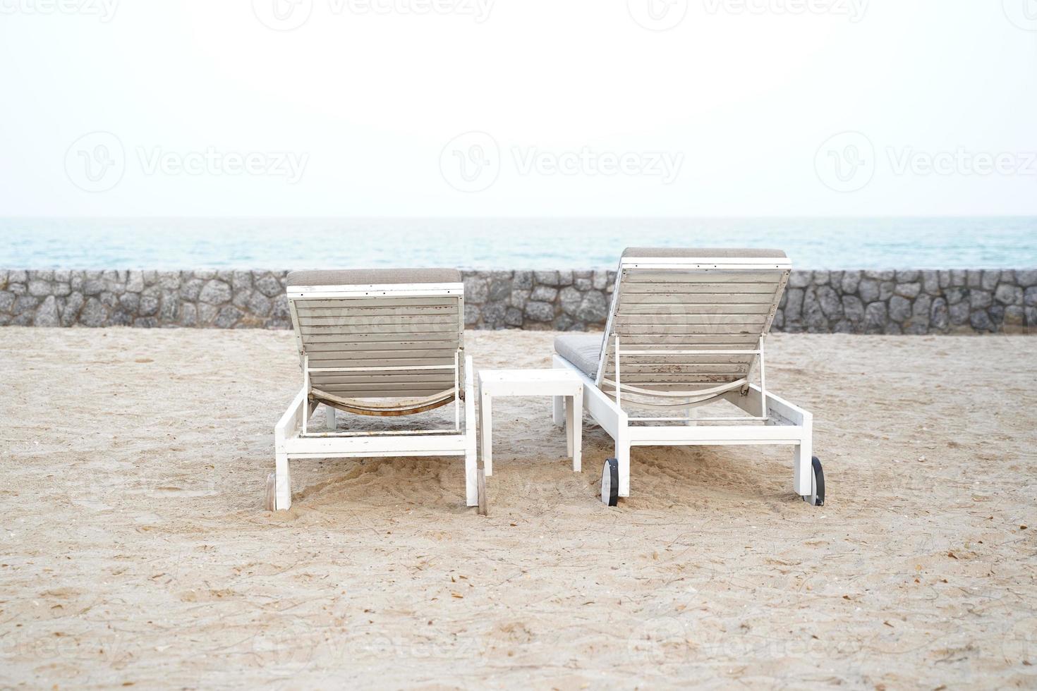 espreguiçadeiras brancas na praia. fundo de verão férias férias. foto