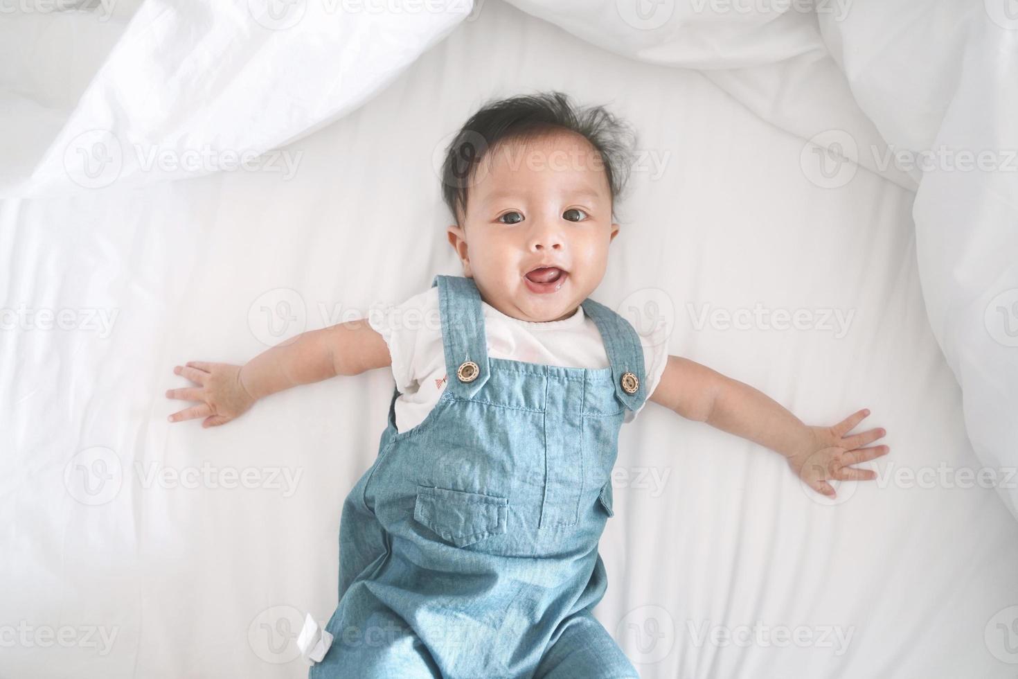 sorridente menina asiática deitada em uma cama. foto