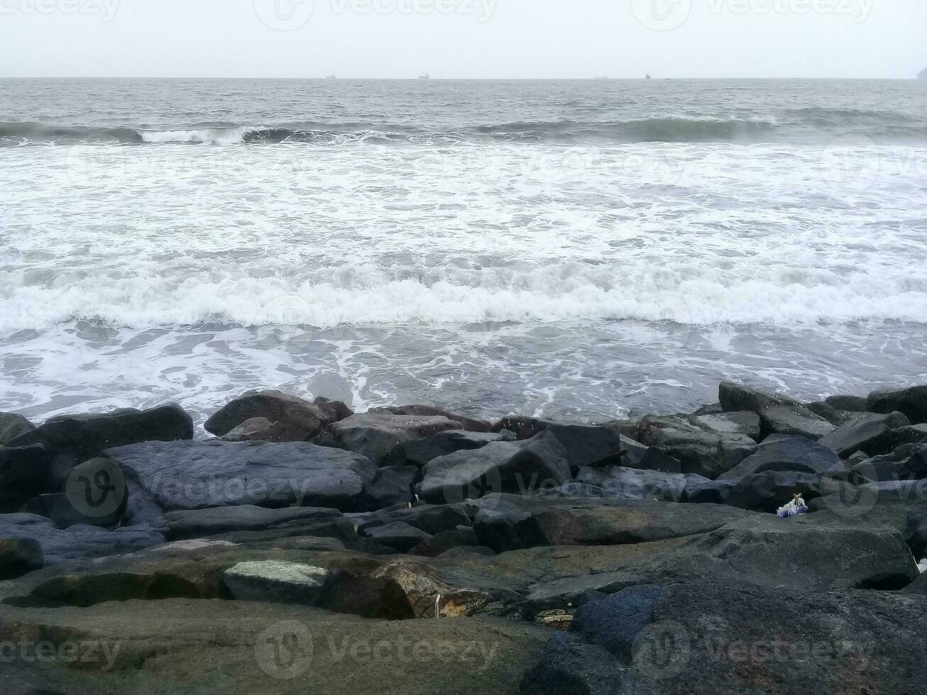 Visão do a ondas e pedras em a de praia foto