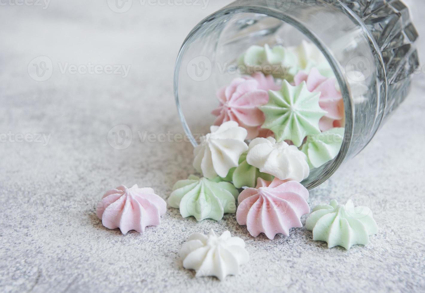 pequenos merengues brancos, rosa e verdes no copo foto