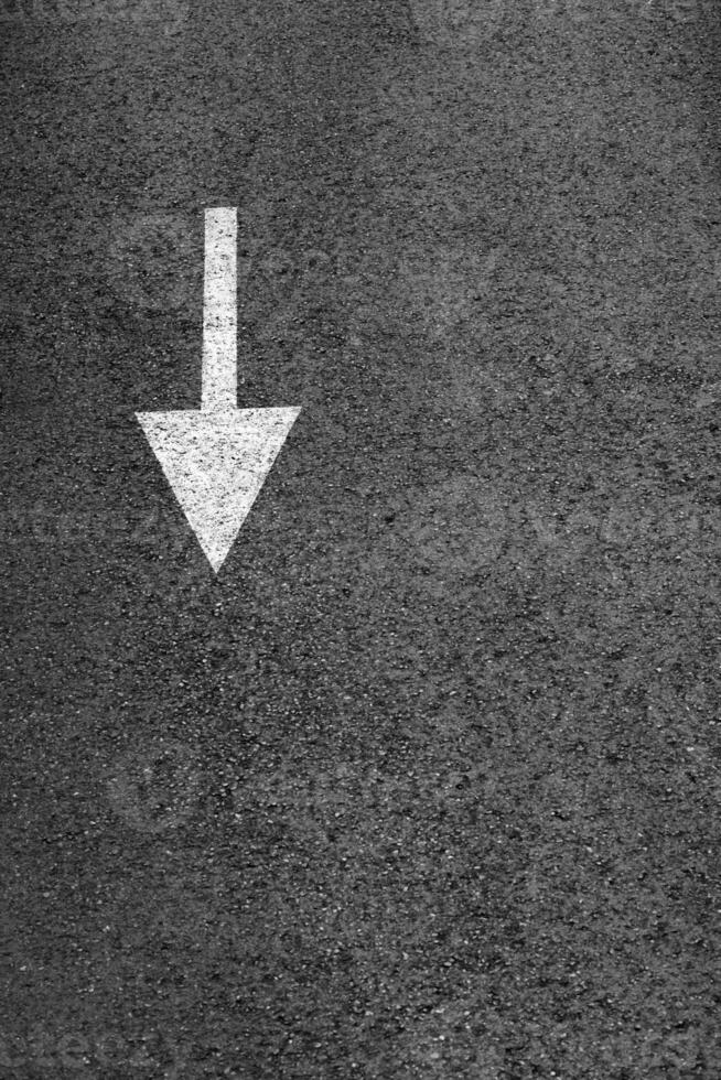 branco seta em a Sombrio cinzento asfalto. foto